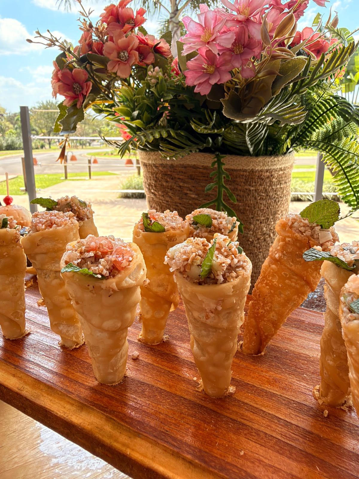 Finger foods apresentados com arranjo floral no evento do Village Manacá