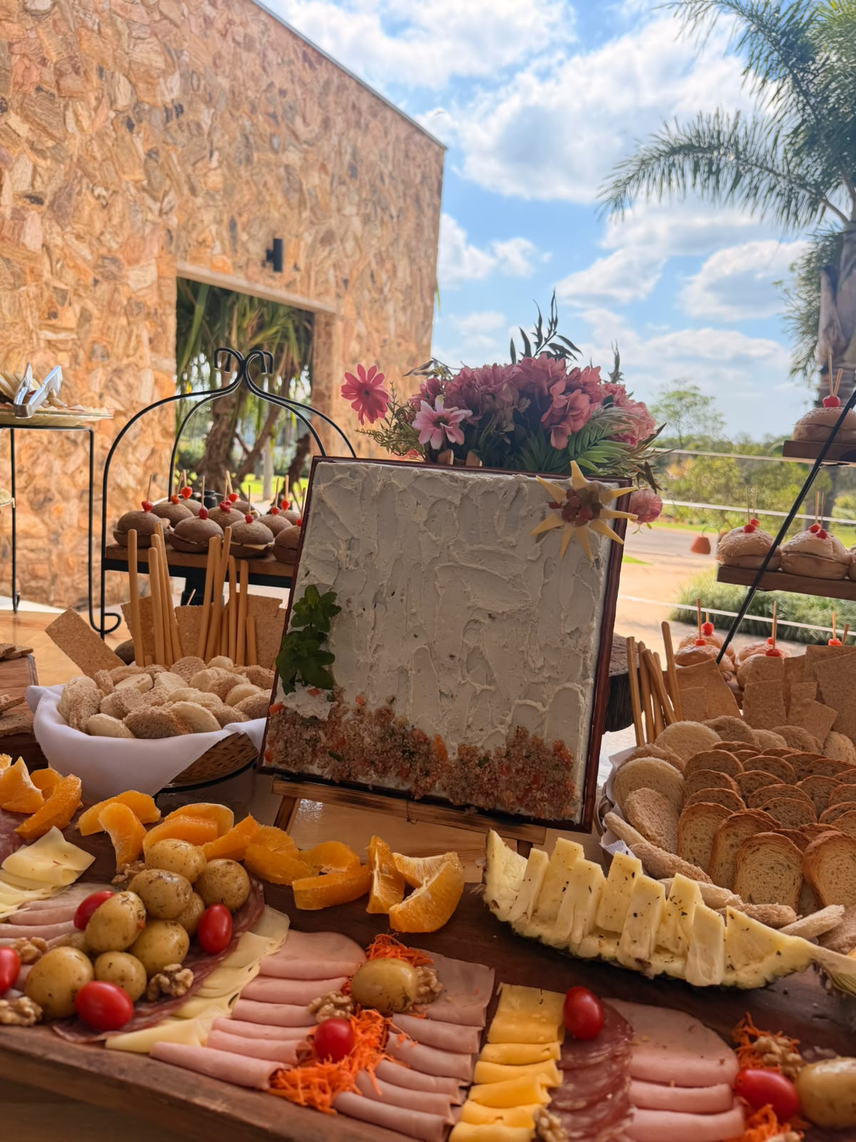 Composição da ilha de frios com flores, pães, queijos e embutidos