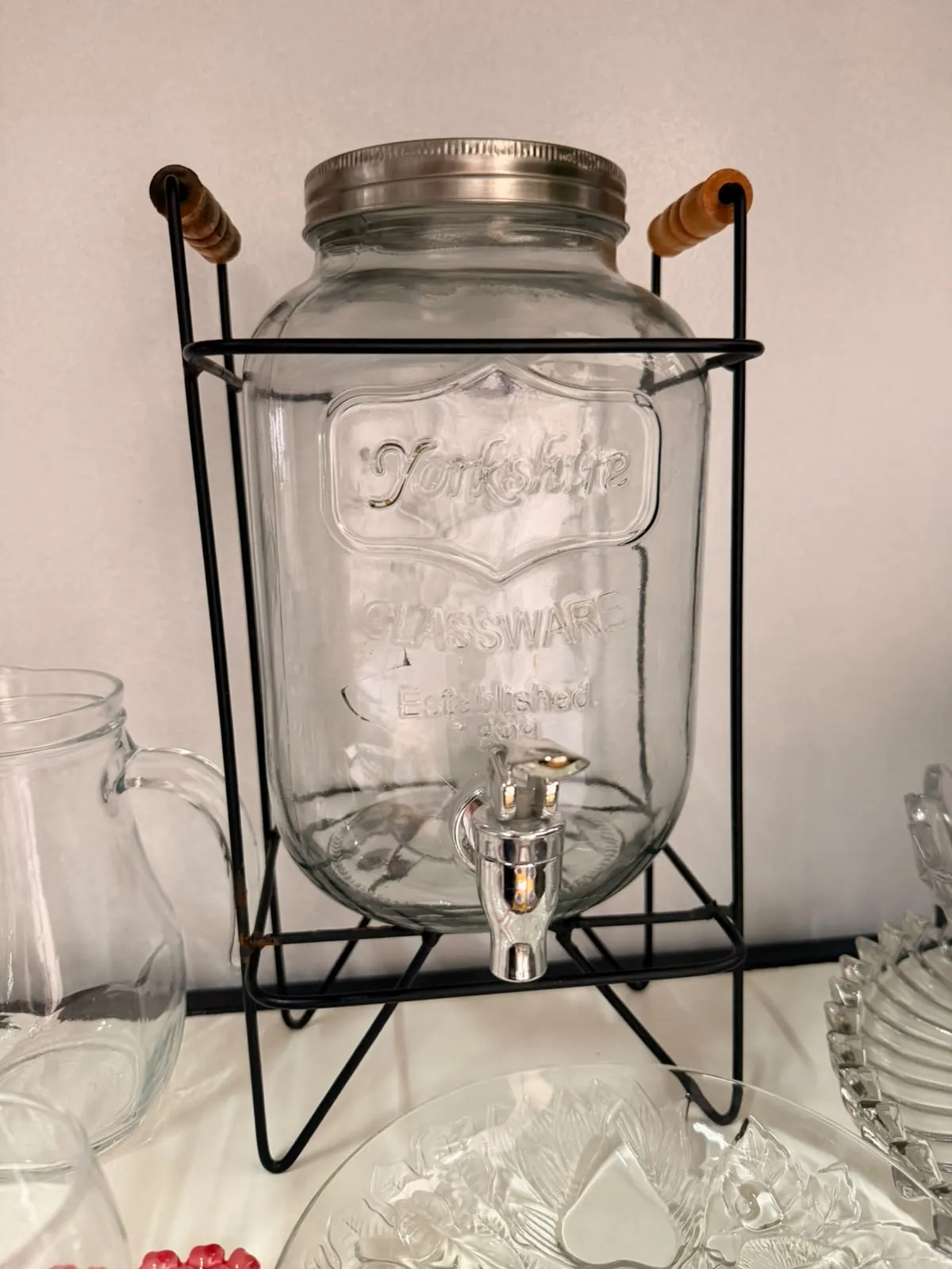 Suqueira de vidro transparente com torneira e suporte de ferro para servir bebidas em festas