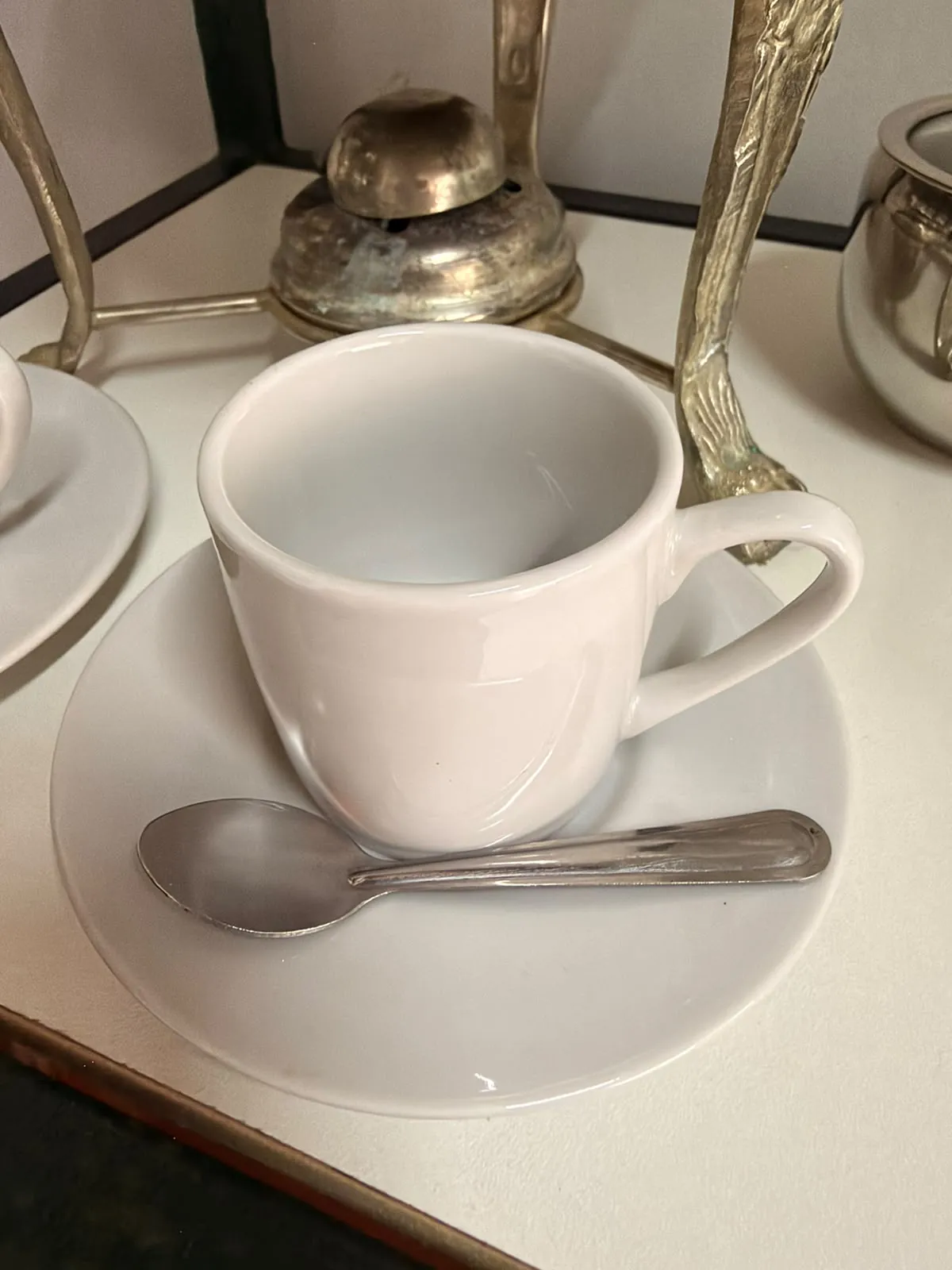 Xícara branca de porcelana com pires e colher de inox para servir café em festas e eventos